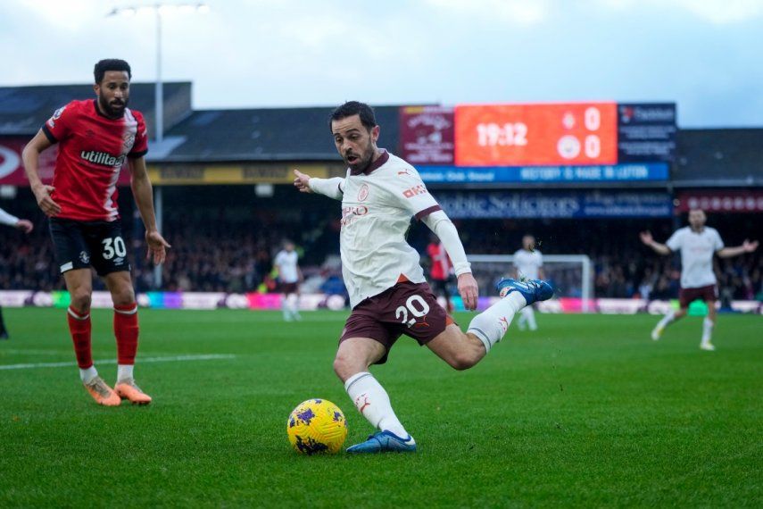 Bernardo Silva del Manchester City dispara el balón frente a Andros Townsend del Luton en el encuentro de la Liga Premier, el domingo 10 de diciembre del 2023.
