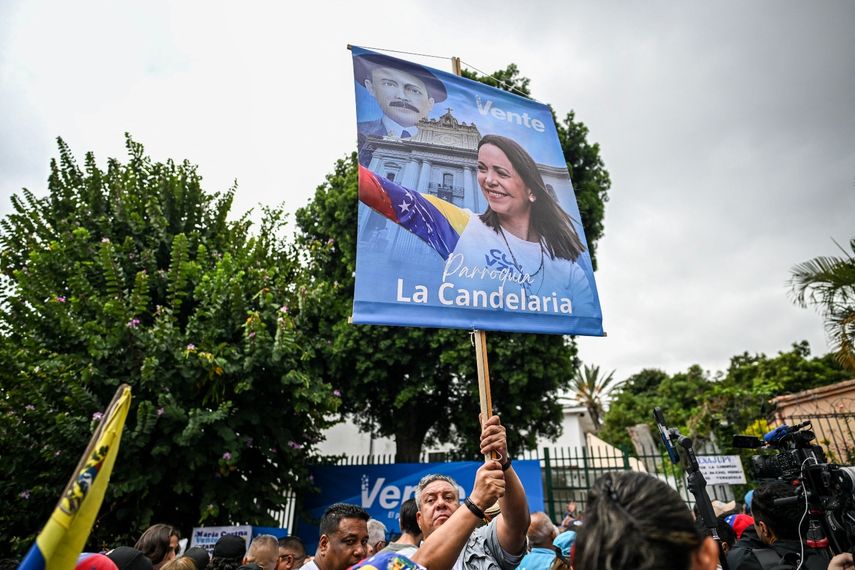 Un simpatizante de la líder de la oposición venezolana y premio Nobel de la Paz, María Corina Machado, sostiene un cartel alusivo mientras se congrega frente a la sede de Vente Venezuela que abrió sus puertas por primera vez en 20 meses, en Caracas el 28 de marzo de 2026.