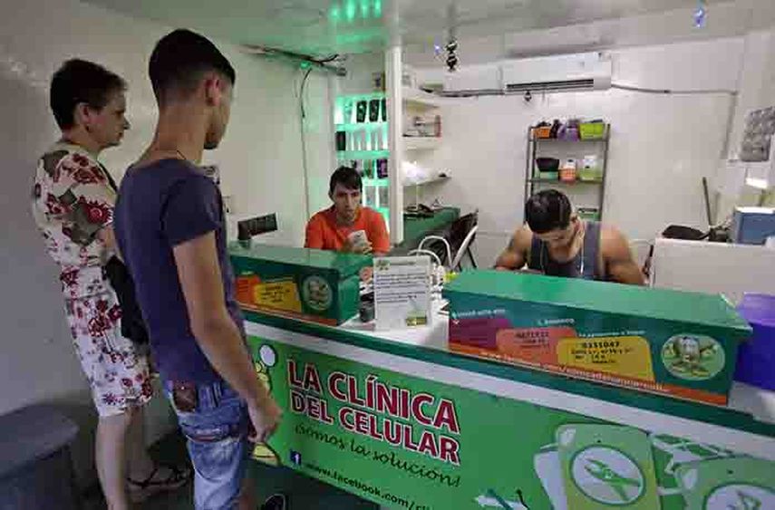 Varias personas esperan para ser atendidos en un centro privado de reparaciones de celulares, en La Habana. (EFE)