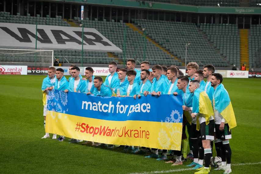Jugadores posan con una pancarta en apoyo a Ucrania antes de un partido amistoso de caridad entre el Legia de Varsovia y el Dynamo de Kiev en el Estadio Ejército Polaco en Varsovia, Polonia, el martes 12 de abril de 2022.