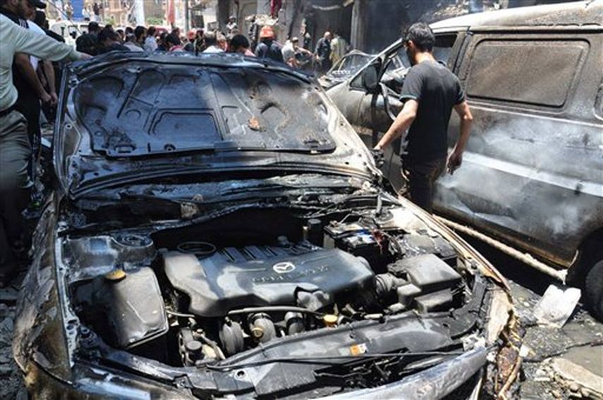 Un sirio camina entre vehículos incendiados donde estalló un coche bomba en un vecindario pro gubernamental en la ciudad de Homs, en el centro de Siria, el jueves 12 de junio de 2014. Al menos siete personas murieron en el atentado y 25 resultaron heri