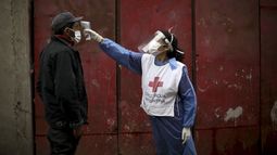 En esta imagen del 6 de junio de 2020, una voluntaria de la Cruz Roja le toma la temperatura a un hombre en el barrio de Fraga durante el cierre ordenado por el gobierno para frenar la propagación del nuevo coronavirus en Buenos Aires. Tras superar la barrera del millón de contagios del nuevo coronavirus, el gobierno de Argentina extendió el viernes 23 de octubre de 2020 la cuarentena hasta el 8 de noviembre aunque con distintas restricciones de acuerdo a cada distrito. Las fronteras seguirán cerradas.&nbsp;