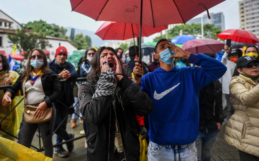 Manifestantes participan en una protesta contra el gobierno del presidente de Colombia, Iván Duque, frente a un hotel donde la Comisión Interamericana de Derechos Humanos está evaluando si hubo abusos por parte de la fuerza pública durante las protestas anteriores, en Bogotá el 9 de junio de 2021.