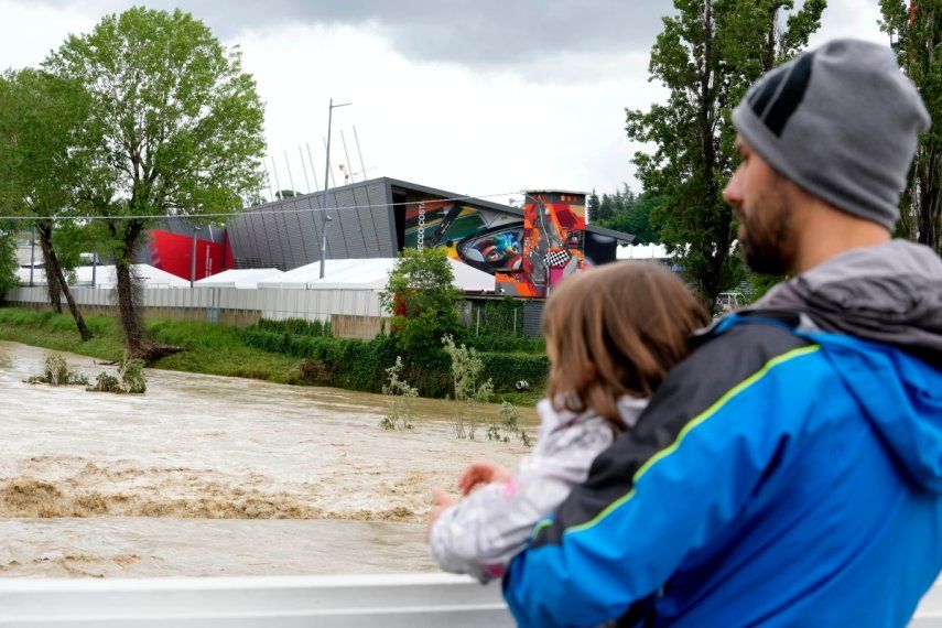 Un hombre con un niño en brazos contempla la crecida del río Santerno, y en el fondo de ve el circuito Enzo e Dino Ferrari en Imola, Italia, 17 de mayo de 2023. Las inundaciones en la región han obligado a cancelar el Gran Premio de Fórmula Uno de la Emilia Romagna, que se debía correr en Imola el próximo fin de semana.&nbsp;
