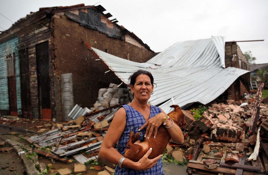 Una mujer posa con su perro frente a su casa destruida por el paso del huracán Irma, en la ciudad central de Remedios.