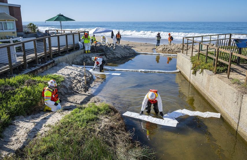 Equipos de limpieza utilizan material absorbente para retirar petróleo que pudiera haber ingresado a un pequeño riachuelo que desemboca en el océano, luego de una fuga en un oleoducto, el jueves 14 de octubre de 2021, en Laguna Beach, California.&nbsp;