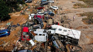 Un hombre se ve de pie junto a autos amontonados sobre unas vías por una inundación en Valencia.