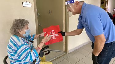 Esteban Bovo entrega una m&aacute;scara de pl&aacute;stico protectora a una se&ntilde;ora de la tercera edad en Hialeah.