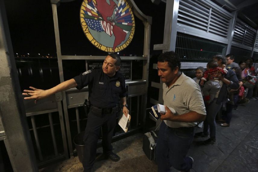 En esta foto del 17 de septiembre de 2019, un agente de la Patrulla Fronteriza señala a dónde ir a una familia migrante nicaragüense que está aplicando para pedir asilo en Estados Unidos. La imagen fue tomada en el Puente Internacional 1 que conecta Nuevo Laredo, México, con Laredo, Texas. El gobierno de Estados Unidos ha impuesto límites para los aplicantes de asilo, lo cual ha transformado a la frontera en un embudo donde cada vez son menos los que pueden entrar legalmente y más los que salen mediante el programa conocido como “Permanecer en México”, una estrategia mediante la que Washington ha devuelto a más de 55.000 personas mientras sus solicitudes de asilo deambulan, con pocas posibilidades de prosperar, por la intrincada burocracia de unas cortes estadounidenses desbordadas.&nbsp;