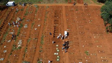 Empleados de cementerio con vestimenta protectora cargan el ataúd con los restos de una persona que murió de complicaciones derivadas del COVID-19 en el cementerio Vila Formosa, Sao Paulo.