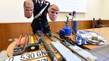 Un miembro de los Carabinari muestra las máscaras con la imagen del presidente de Estados Unidos, usadas por dos ladrones, durante una rueda de prensa en Turín.