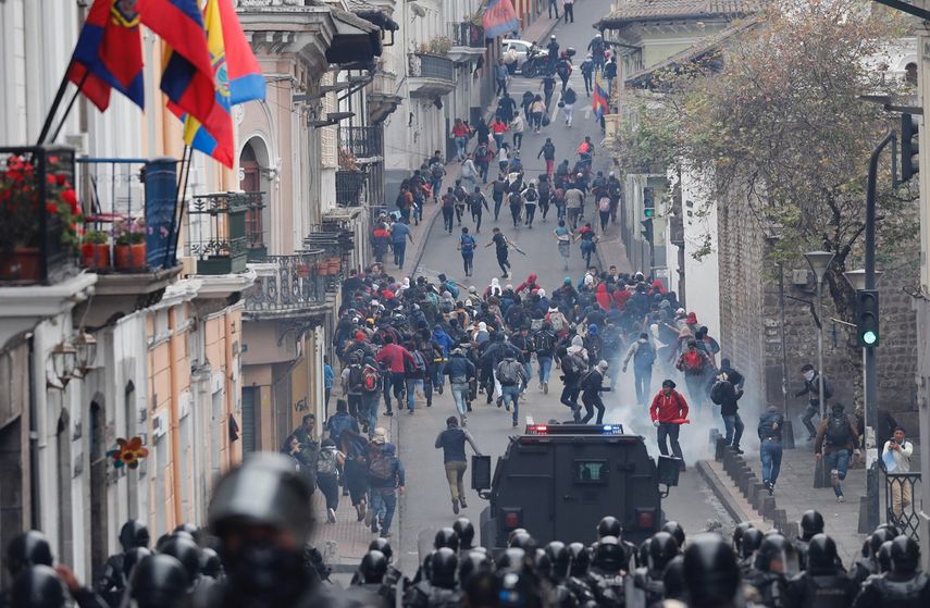 Manifestantes huyen ante&nbsp;la fuerte presencia policial durante una protesta contra la eliminaci&oacute;n de los subsidios al combustible anunciada por el presidente Len&iacute;n Moreno, en Quito, Ecuador.
