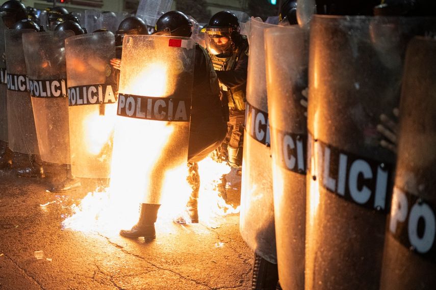 Un agente de la policía antidisturbios es alcanzado por una bomba molotov lanzada por manifestantes durante una manifestación antigubernamental en Lima el 21 de septiembre de 2025.