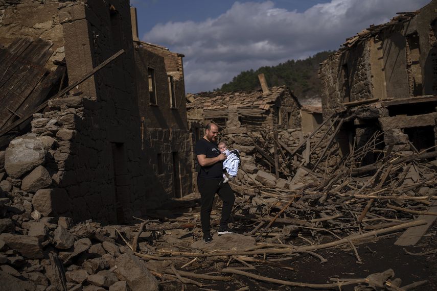 Rafael Monlina, de 33 años, sostiene a su hijo de cuatro meses, Marcos, mientras visitan el antiguo pueblo de Aceredo, sumergido hace tres décadas cuando una presa hidroeléctrica inundó el valle, emerge debido a la sequía en el embalse de Lindoso, en el noroeste de España, el sábado 12 de febrero de 2022.&nbsp;
