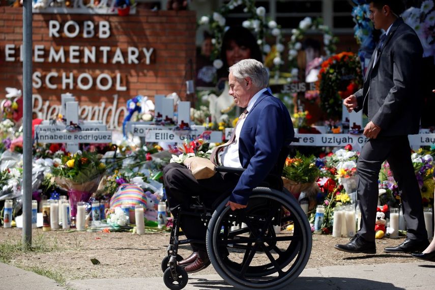 El gobernador de Texas, Greg Abbott, pasa frente a un altar improvisado afuera de la Escuela Primaria Robb en honor a las víctimas de una masacre escolar, el 29 de mayo de 2022, en Uvalde, Texas.