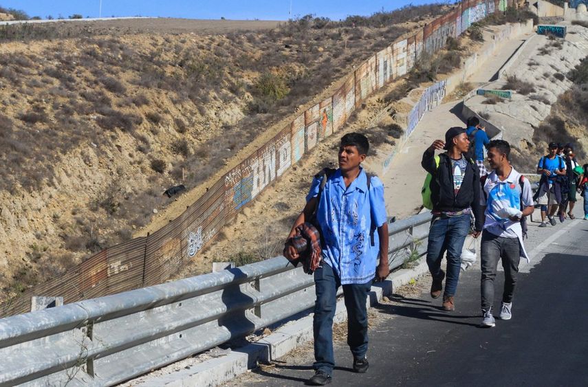 Un grupo de inmigrantes centroamericanos caminan a lo largo de la valla que separa a México y EEUU en Tijuana.