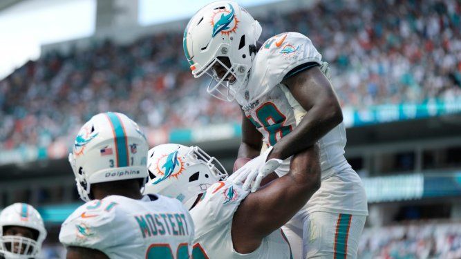 El defensive tackle Christian Wilkins (94) levanta a su compañero de los Dolphins de Miami, DeVon Achane (28), después de que anotó un touchdown en la segunda mitad del partido ante los Broncos de Denver, el domingo 24 de septiembre de 2023, en Miami Gardens, Florida.&nbsp;