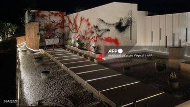 Esta fotografía tomada y publicada el 6 de agosto de 2024 por el colectivo de desobediencia civil Futuro Vegetal muestra a dos activistas sosteniendo una pancarta que dice Ayuda al planeta, cómete a los ricos, abolid la policía después de pintar con aerosol la casa de la estrella del fútbol argentino Lionel Messi en Ibiza.