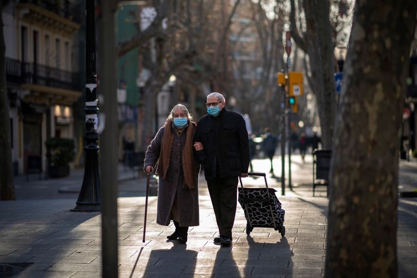 Una pareja con mascarillas para protegerse del coronavirus camina por una calle el 27 de enero de 2021, en Barcelona, España.