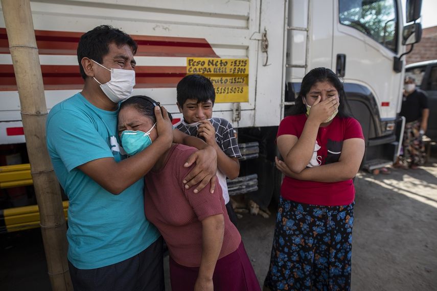 Familiares lloran mientras observan como operarios de la funeraria Piedrangel retiran el cuerpo de un pariente que se cree que murió a causa del nuevo coronavirus, en Lima, Perú, el 11 de mayo de 2020. Pese a las estrictas medidas para controlar el virus, Perú es uno de los países más afectados por la pandemia.