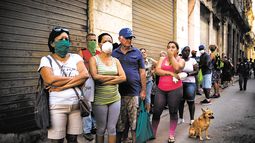 La gente hace fila para comprar alimentos, algunos usando m&aacute;scarillas como precauci&oacute;n contra la propagaci&oacute;n del nuevo coronavirus.