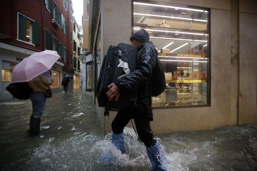 Un hombre carga su equipaje al caminar entre el agua en Venecia el viernes 15 de noviembre de 2019.&nbsp;