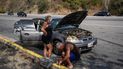 Un hombre trata de reparar su automóvil, estacionado a un costado de la carretera entre La Guaira y Caracas, Venezuela, el 19 de abril del 2022.