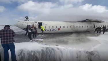 Captura del pantalla cuando las personas escapan del avión tras volcarse en una pista colmada de nieve.&nbsp;