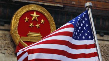 Una bandera estadounidense junto al emblema nacional de China en una ceremonia de bienvenida a visitantes estadounidenses.