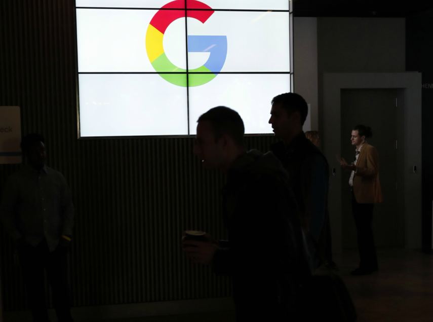 Unas personas caminan junto a un logo del gigante tecnológico Google&nbsp;que presentó sus nuevos teléfonos móviles&nbsp;Google&nbsp;Pixel 2 y&nbsp;Google&nbsp;Pixel 2 XL.&nbsp;