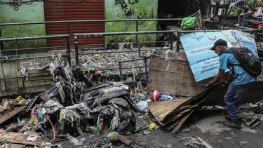 &nbsp;Un hombre intenta quitar los escombros que cubren una motocicleta luego del paso de una tormenta.