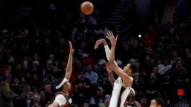 El francés Victor Wembanyama, de los Spurs de San Antonio, dispara entre Moses Brown (izquierda) y Jerami Grant (derecha, atrás), de los Trail Blazers de Portland, durante el encuentro del jueves 28 de diciembre de 2023&nbsp;