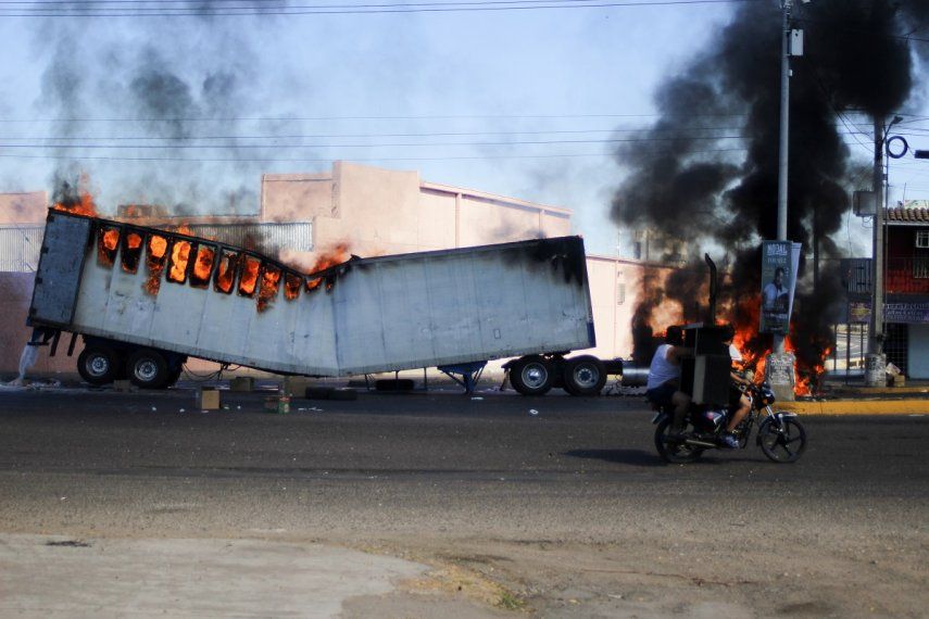 Dos hombres a bordo de una motocicleta pasan junto a un camión en llamas en las calles de Culiacán, en el estado de Sinaloa, el 5 de enero de 2023.