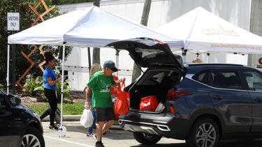 Un voluntario deposita bolsas con alimentos en el ba&uacute;l de un autom&oacute;vil.