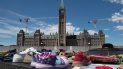 Zapatos, letreros y tabaco son colocados frente al Parlamento, en Ottawa, Ontario, el lunes 31 de mayo de 2021, en reconocimiento al descubrimiento de los cadáveres de decenas de niños en el sitio de un antiguo internado en Kamloops, Columbia Británica.