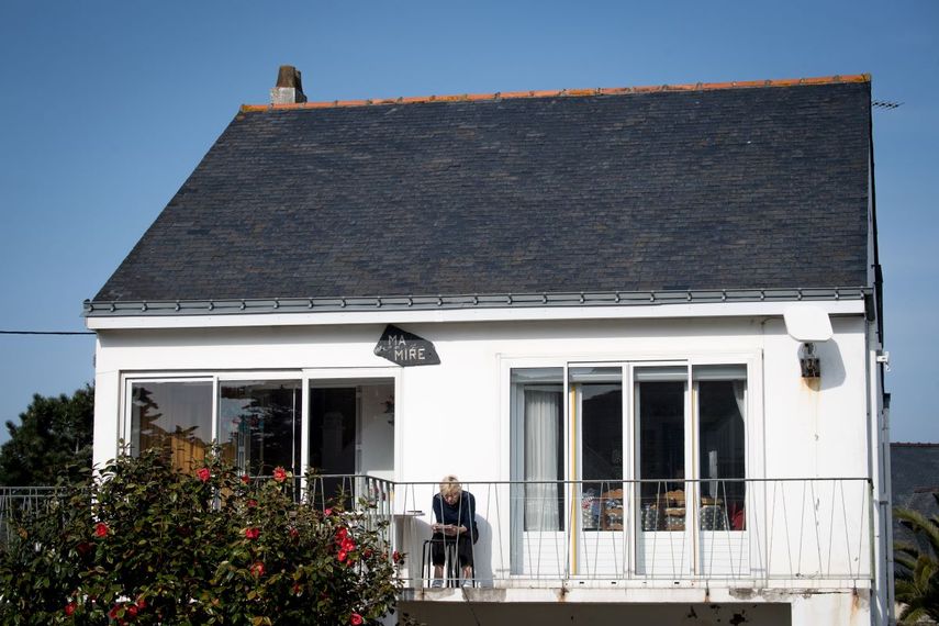 Una mujer juega crucigramas mientras se sienta en el balcon de su casa en La Baule, al oeste de Francia, el 27 de marzo de 2020. Los frances permanecen en condiciones de aislamiento, el país está cerrado para detener la propagación de la pandemia de Covid-19.