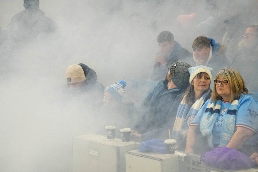 Humo de bengalas satura el aire en las tribunas antes del partido por la Copa de la Liga inglesa entre el Manchester City y el Liverpool, en el Estadio Etihad de Manchester, Inglaterra, el jueves 22 de diciembre de 2022.