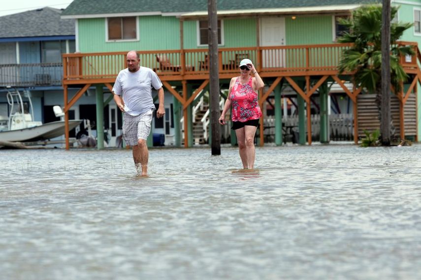 Adam Sides camina a través de una calle inundada con su madre, Cindy, tras el paso de la tormenta tropical Alberto, el jueves 20 de junio de 2024, en Surfside Beach, Texas.