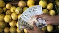 Un cliente muestra billetes de bolívares y de dólar, en un mercado de Caracas