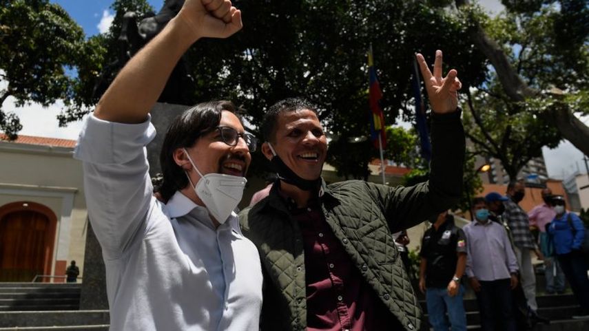 El recientemente indultado y liberado diputado opositor Gilber Caro (derecha) muestra el letrero de la Victoria junto al diputado opositor Freddy Guevara, mientras este &uacute;ltimo abandona la embajada de Chile donde se hab&iacute;a refugiado en 2017, en Caracas.