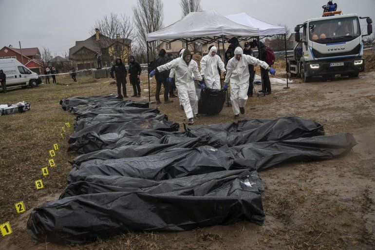 Trabajadores forenses trasladar el cuerpo de un civil asesinado durante la guerra con Rusia tras sacarlo de una fosa común en Kiev, Ucrania, el 8 de abril de 2022.