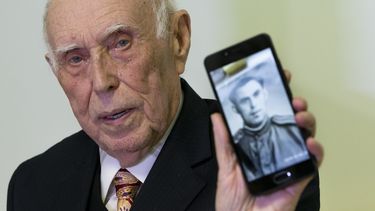 El sobreviviente del Holocausto Mikhail Spektr, de 86 años, muestra una foto suya en uniforme del ejército soviético a la prensa durante la ceremonia del encendido del menorá en Moscú, Rusia, el 22 de diciembre de 2019. 