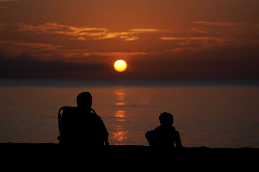 Dos personas observan el ocaso en Surfside, Florida. Para desconcierto de los meteorólogos, no ha habido un solo huracán en el Atlántico desde principios de julio hasta fines de agosto del 2022.