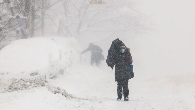Los autos están casi enterrados en nieve, mientras dos personas caminan durante una tormenta de nieve en el área de Hamilton Heights en el distrito de Manhattan de la ciudad de Nueva York el 23 de febrero de 2026.