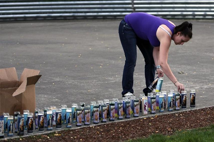 Una residente coloca varias velas mientras prepara una vigilia en Stewart Park en memoria de las víctimas de un tiroteo perpetrado en el centro de estudios superiores Umpqua Community College, en Roseburg, Oregón. (EFE)