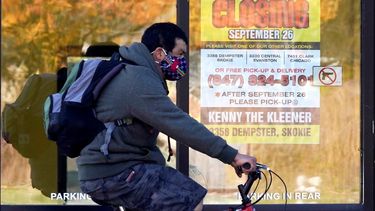 Un hombre pasa en su bicicleta junto a un negocio cerrado en Wilmette, Illinois. Con más encierros inminentes y meses antes de la amplia distribución de una vacuna, algunos gobernadores en Estados Unidos están pidiendo más ayuda federal para el que se anuncia como un invierno sombrío.