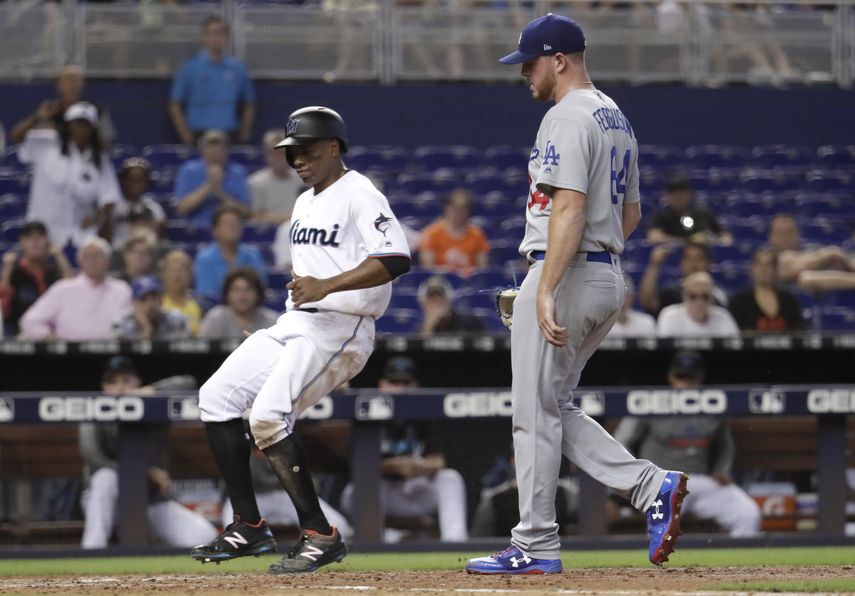 Curtis Granderson, izquierda, de los Marlins de Miami anota en un lanzamiento descontrolado del abridor de los Dodgers de Los Ángeles, Caleb Ferguson, derecha, durante la sexta entrada del juego de béisbol, el jueves 15 de agosto de 2019, en Miami.