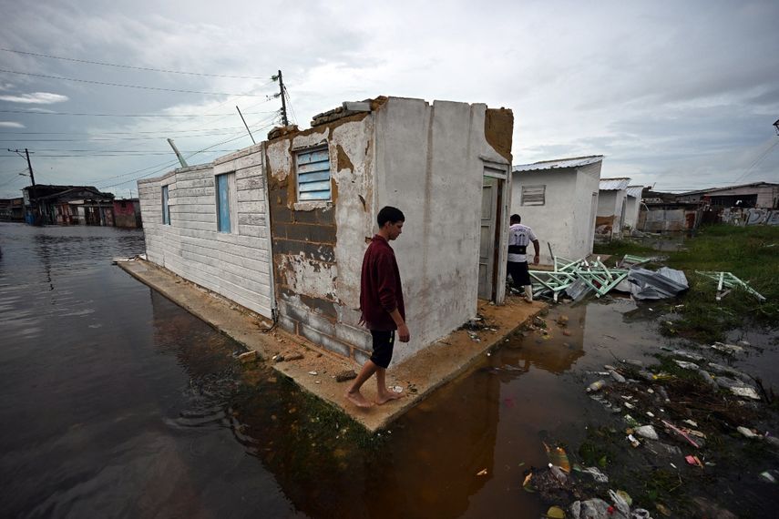 Un joven camina afuera de una casa dañada y rodeado de agua de lluvia tras el paso del huracán Rafel en Batabano, provincia de Mayabeque, Cuba, el 7 de noviembre de 2024.