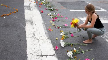 Una mujer coloca flores en la esquina de la Fourth Street y Water Street, en Charlottesville, Virginia, donde un auto arremetió contra una multitud de personas este sábado 12 de agosto, con el saldo de tres personas muertas.