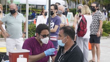 Carlos Anacleto cierra los ojos mientras recibe la vacuna Pfizer COVID-19 de manos del enfermero Jorge Tase, mientras otros esperan su turno, el miércoles 4 de agosto de 2021 en Miami Beach, Florida.&nbsp; 